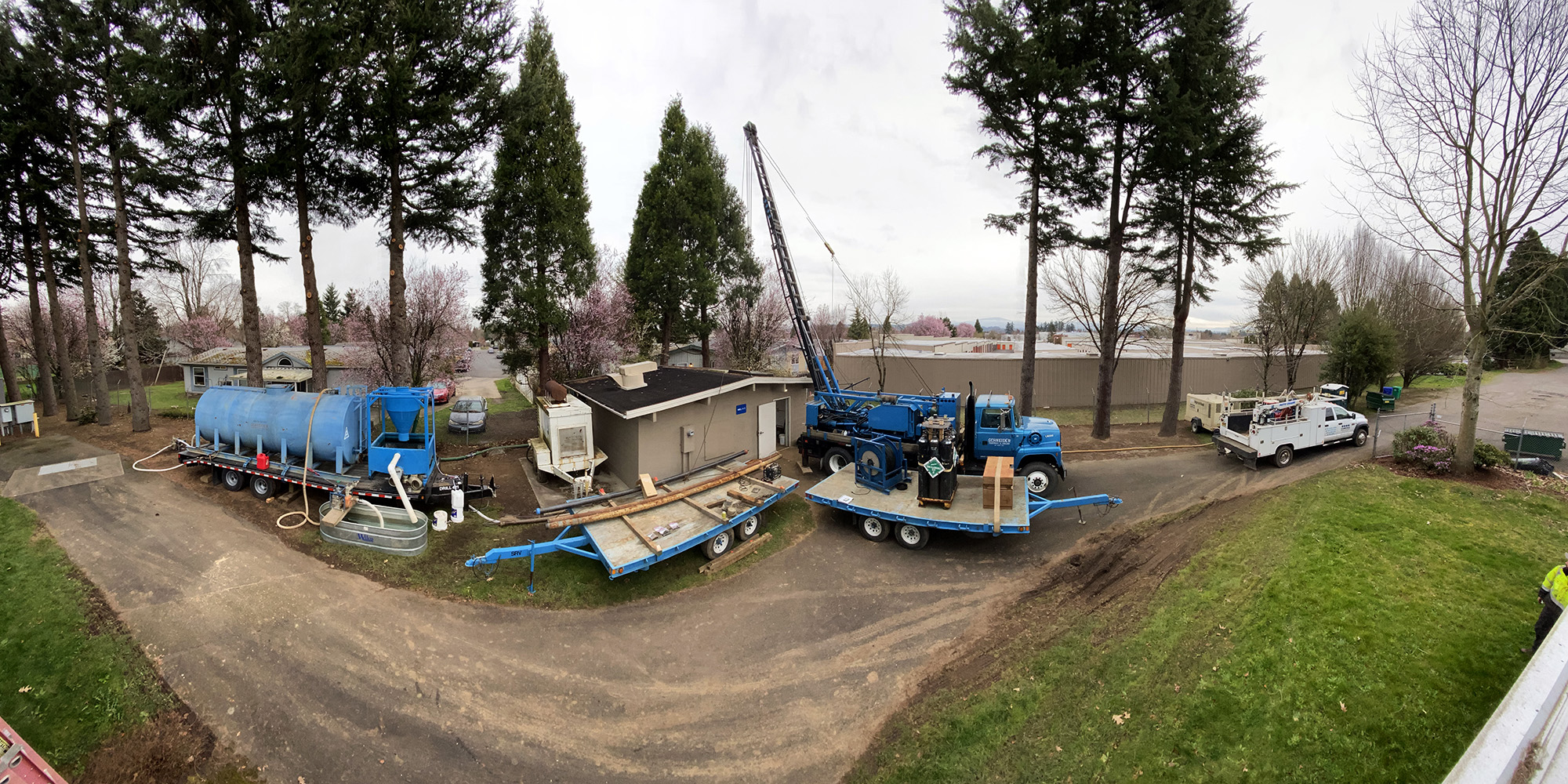 Schneider Water Services Well Rehabilitation project with three trucks and a house